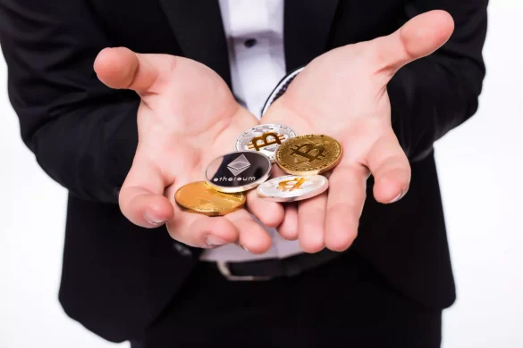 Homem com moedas com símbolos de criptos na mão.