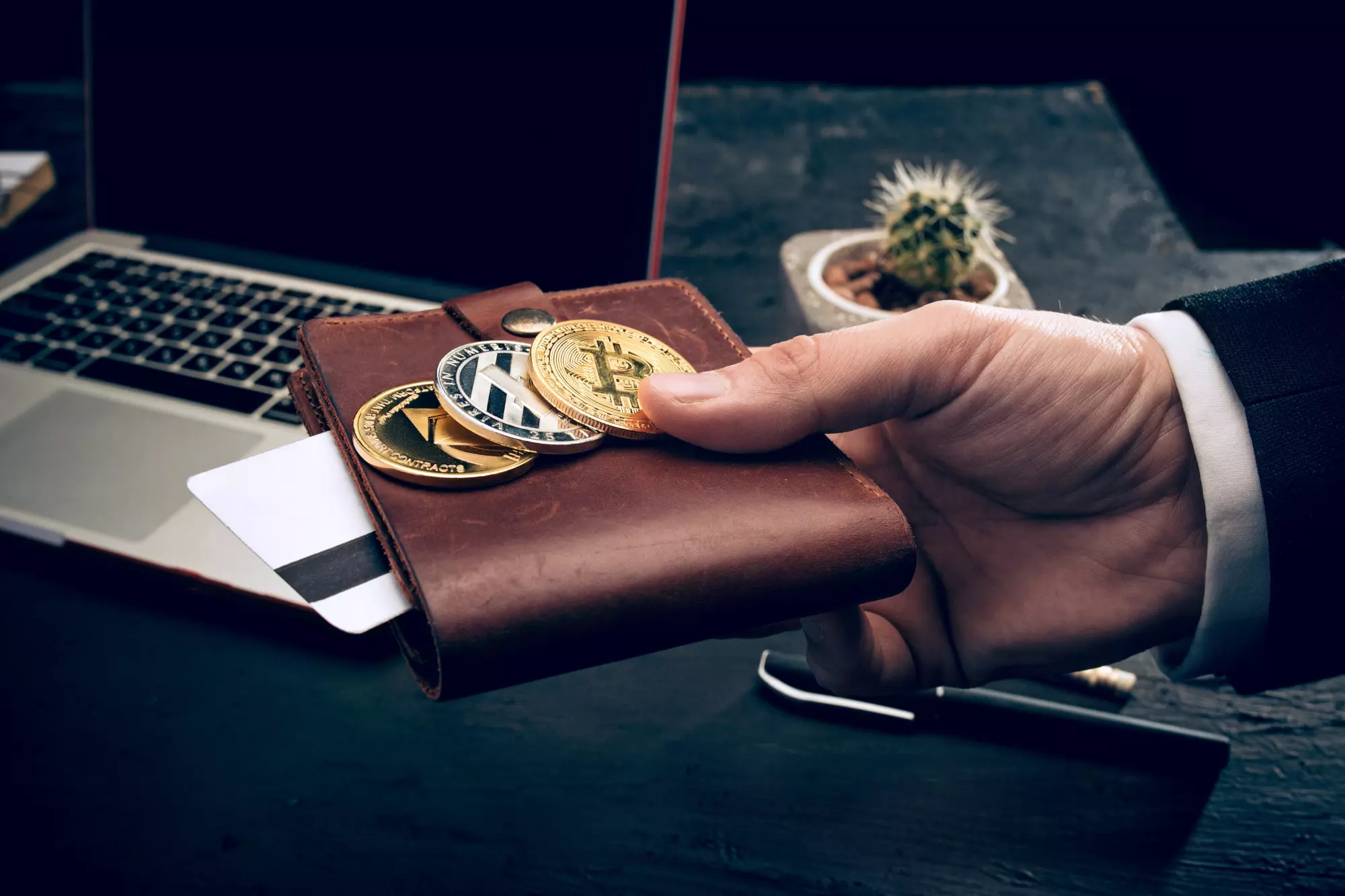 Criptomoedas: Homem com 3 moedas fisicas representando Criptomoedas sobre a carteira. 